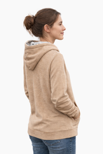 Load image into Gallery viewer, Woman wearing a beige hoodie on a white background Rudy Adventures hoodie worn outdoors in Colorado